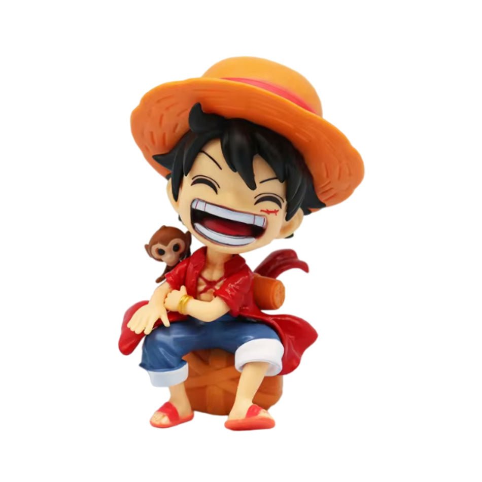 Chibi One Piece figure of Luffy laughing in his straw hat and red shirt, sitting on a bundle with a small monkey on his shoulder
